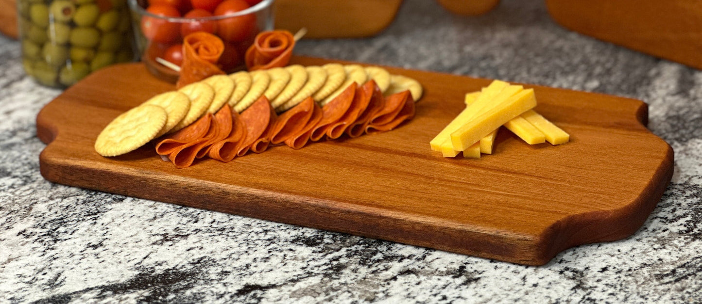 Mahogany red hardwood tray style charcuterie board with cherry tomato, meat, olive jar, cheese and crackers