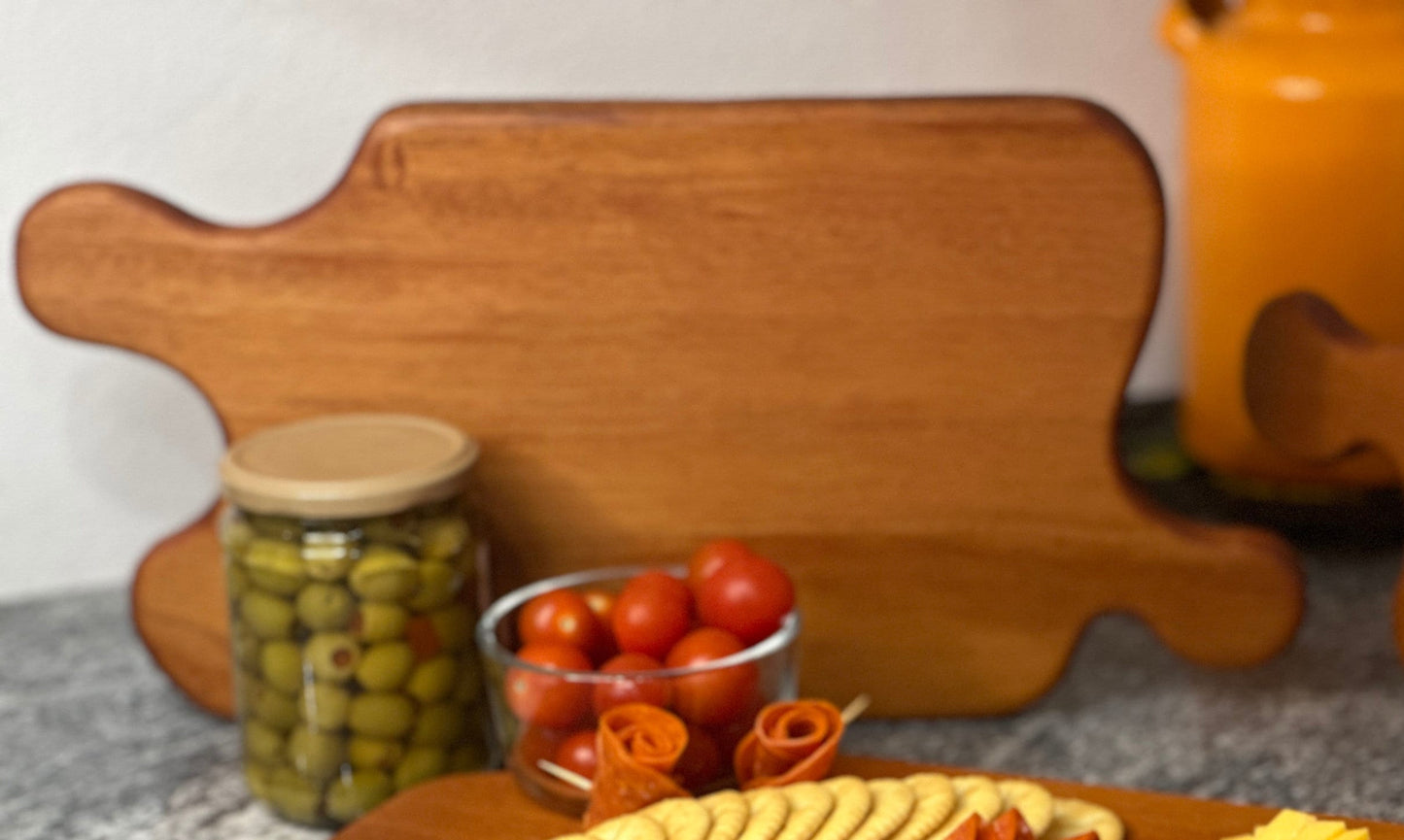 Mahogany red hardwood jigsaw puzzle shaped charcuterie board with cherry tomato, olives, meat and crackers