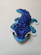 A 3D-printed articulated gecko toy in vibrant two-tone blue, black, and white, photographed on a plain off-white background.