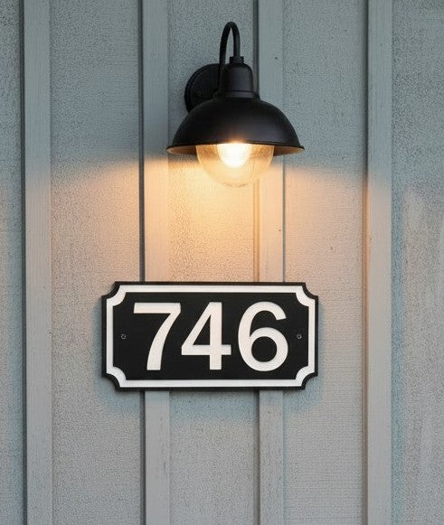 Black and white 5-inch HDPE address sign mounted on exterior siding beneath an outdoor light