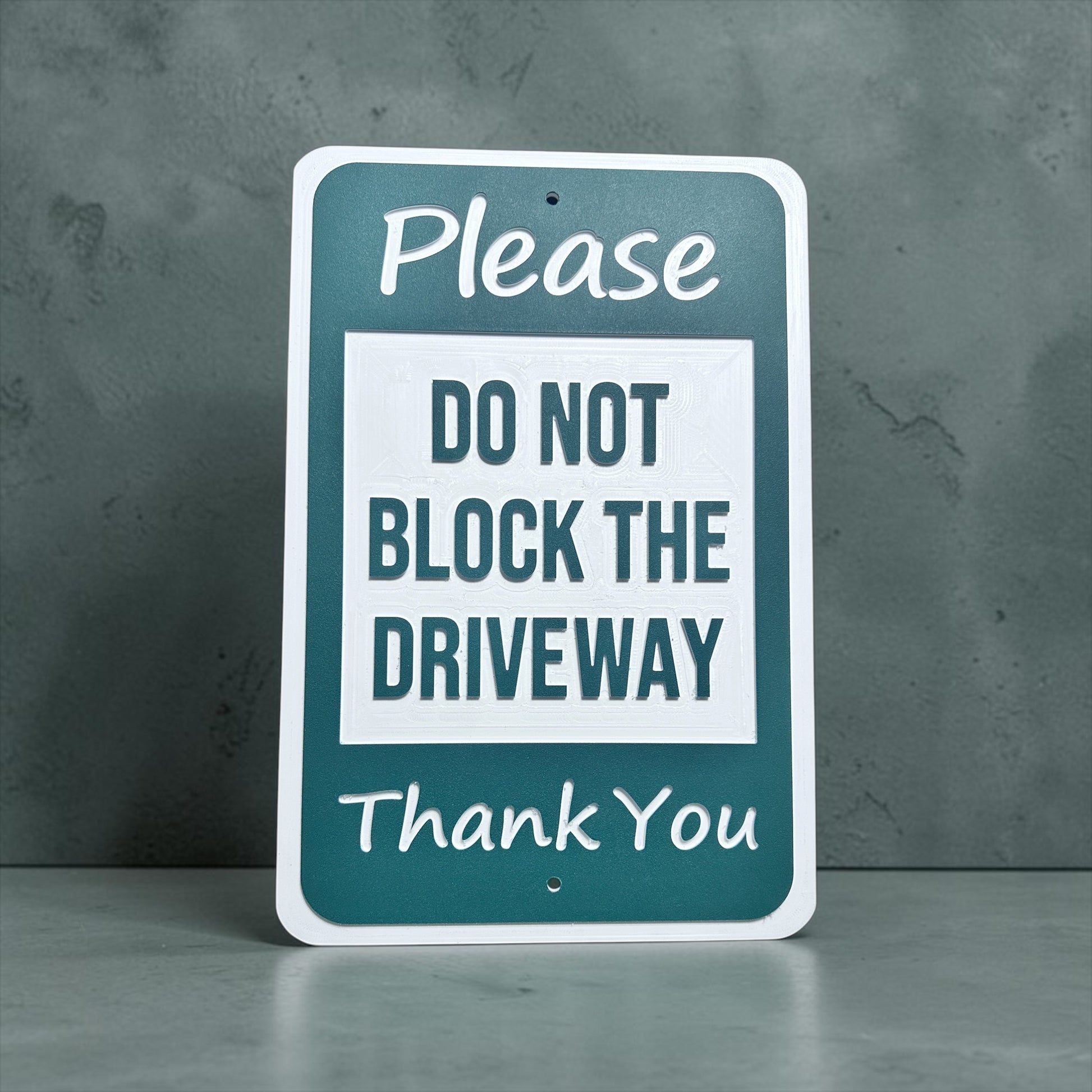 Sign with text 'Please do not block the driveway thank you' with grey background