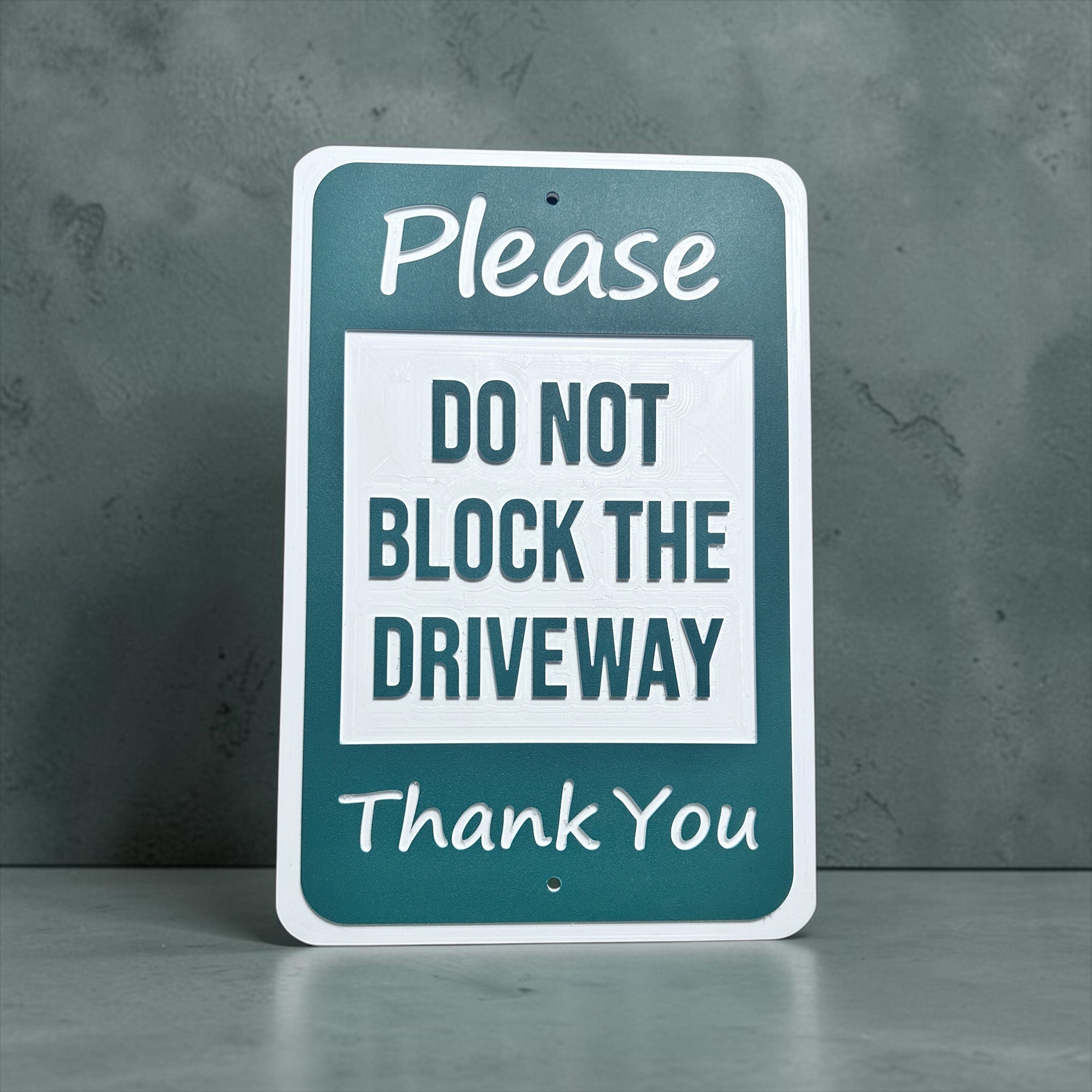 Sign with text 'Please do not block the driveway thank you' with grey background