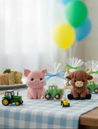 3d printed "Knitted" style farm animal toys on a table with green tractor cookies, balloons and cake in the background.