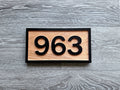 Custom horizontal wood address sign with raised black house numbers and border on a natural wood face