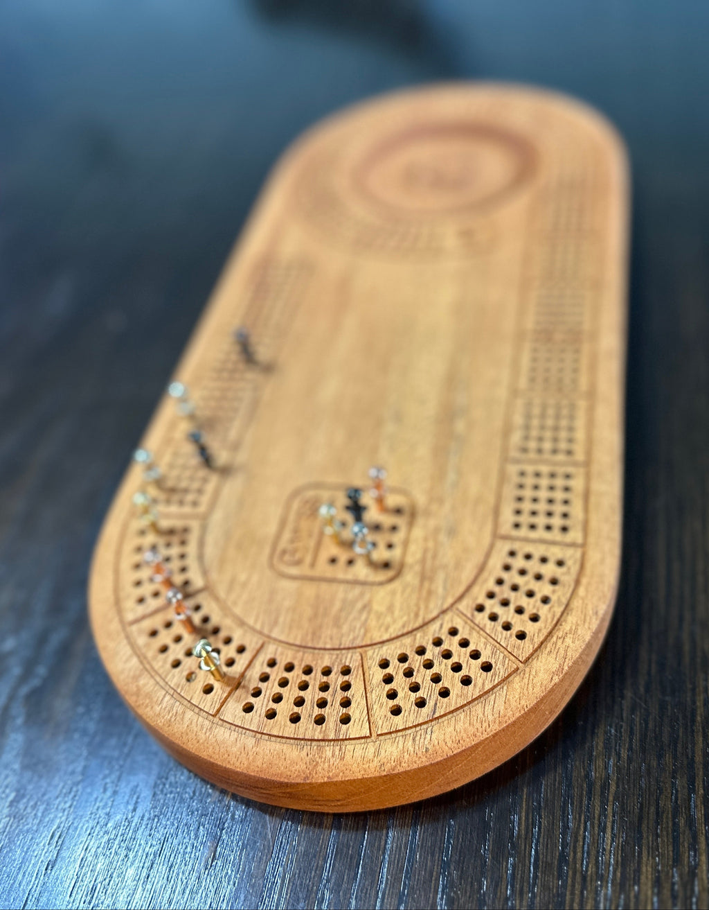 Wooden cribbage board with pegs on a dark surface
