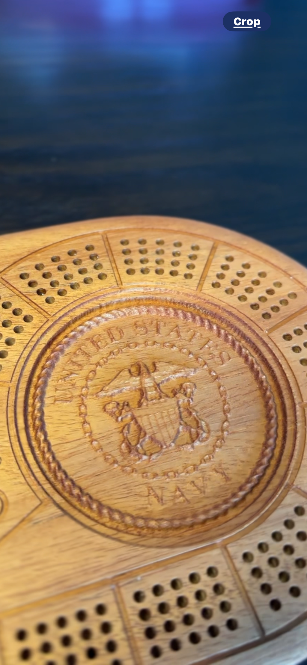 Zoomed in view of oval 4 player hardwood cribbage board with custom US Navy 3d carving