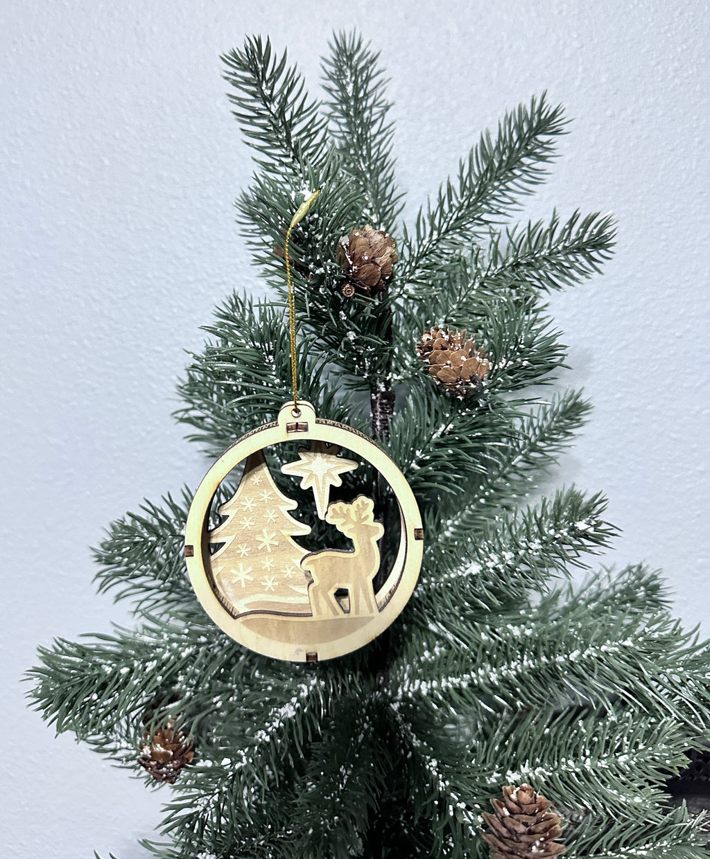 Close-up 3d wooden ornament with deer, tree, and stars.