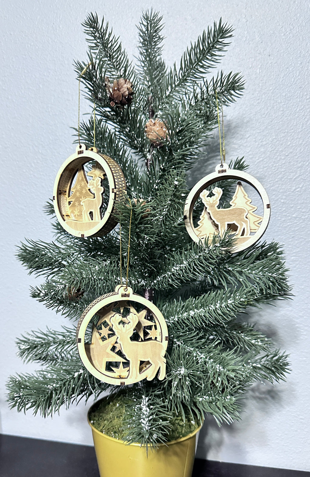 Angled view of 3 hanging 3d wooden Christmas ornaments.