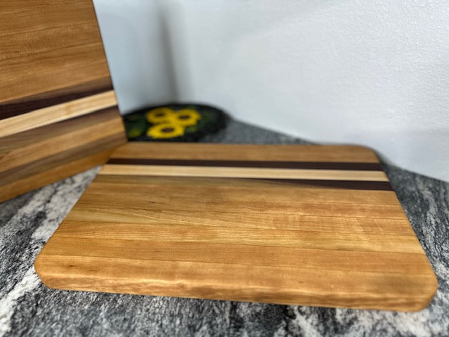 Cherry maple walnut striped hardwood rectangle cutting boards displayed by a cast iron decor with sunflowers