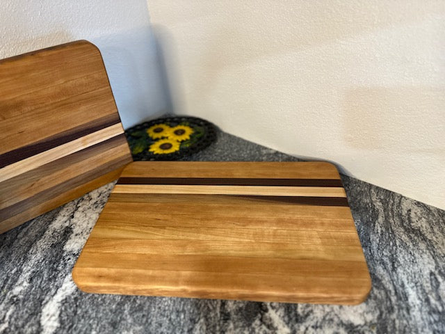Cherry maple walnut striped hardwood rectangle cutting boards displayed by a cast iron decor with sunflowers