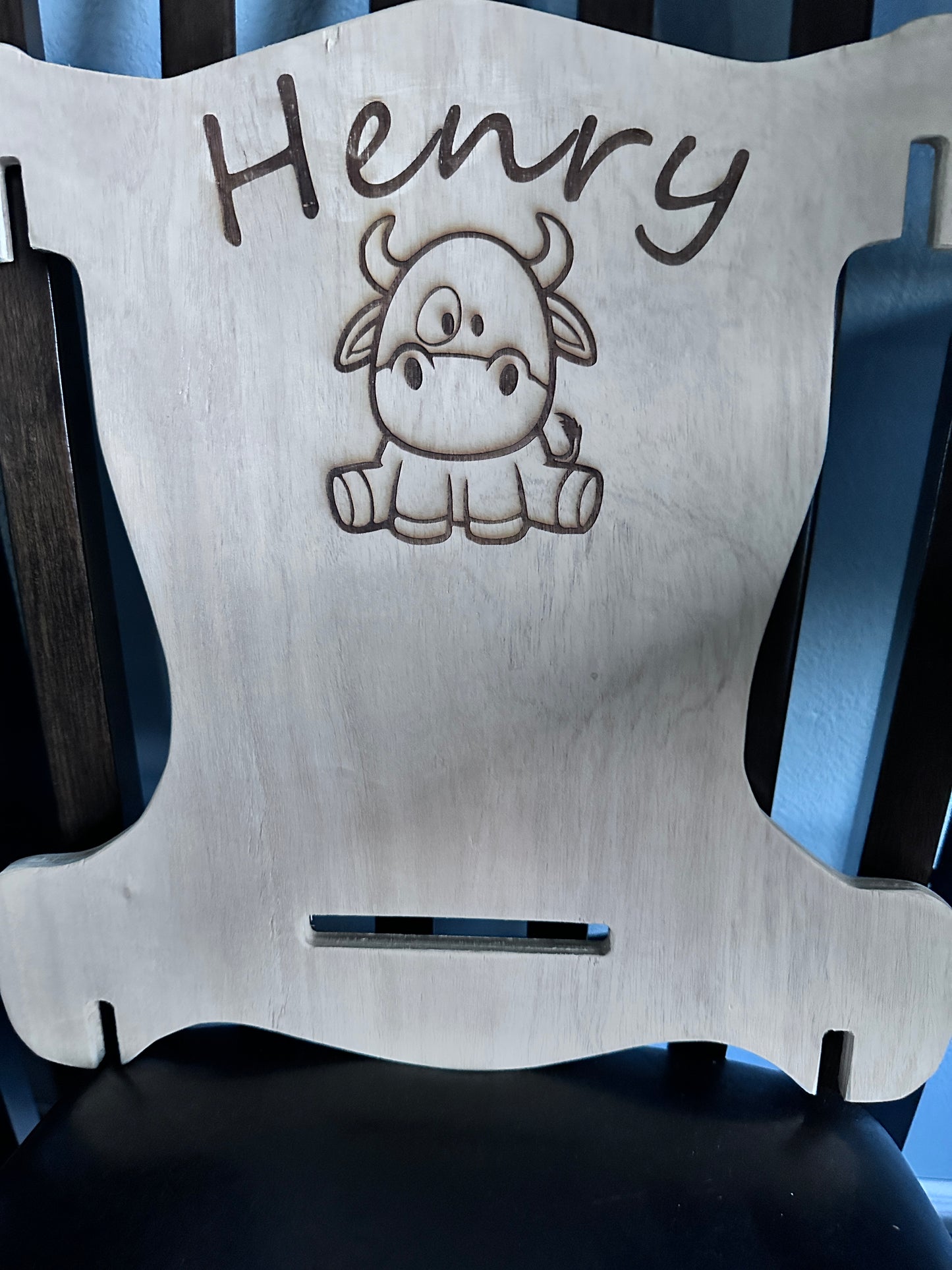 Natural wood puzzle rocking chair for a toddler with laser engraved name "Henry" and a laser engraved cartoon cow on the chair back.