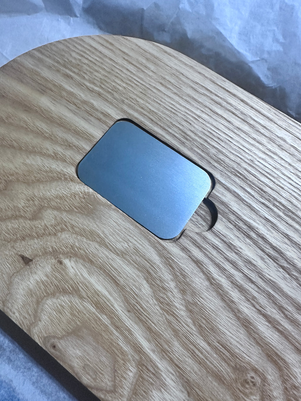 bottom of Oval hardwood cribbage board showing metal cover of peg pocket