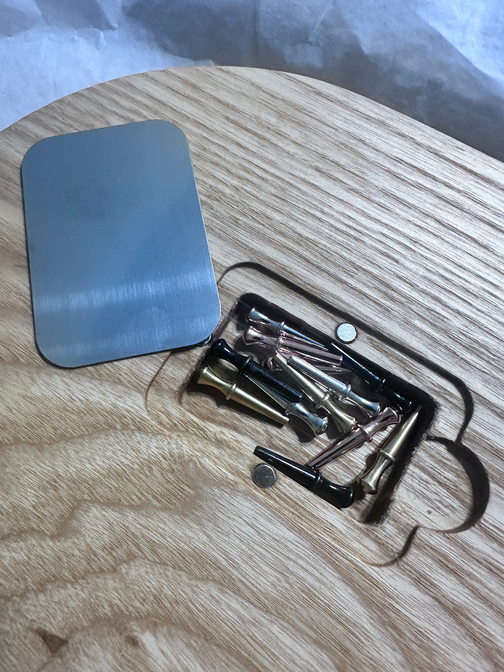 bottom of Oval hardwood cribbage board showing open magnetic peg pocket with 12 pegs and metal cover