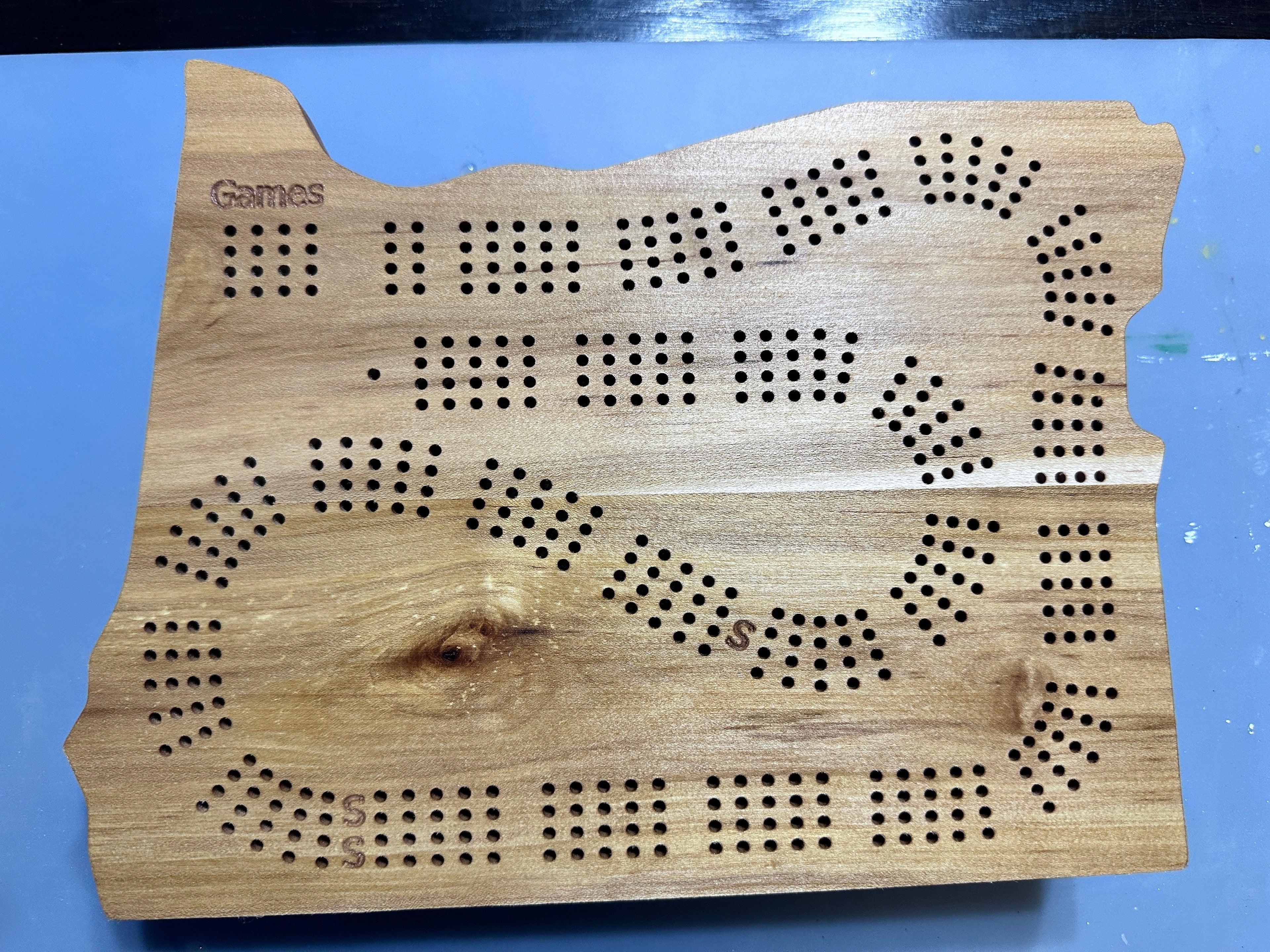Calico maple 4player cribbage board state of Oregon shape on a blue background