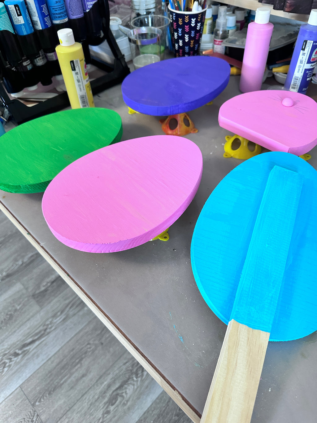 green, purple, pink and blue egg stakes set on work table to dry