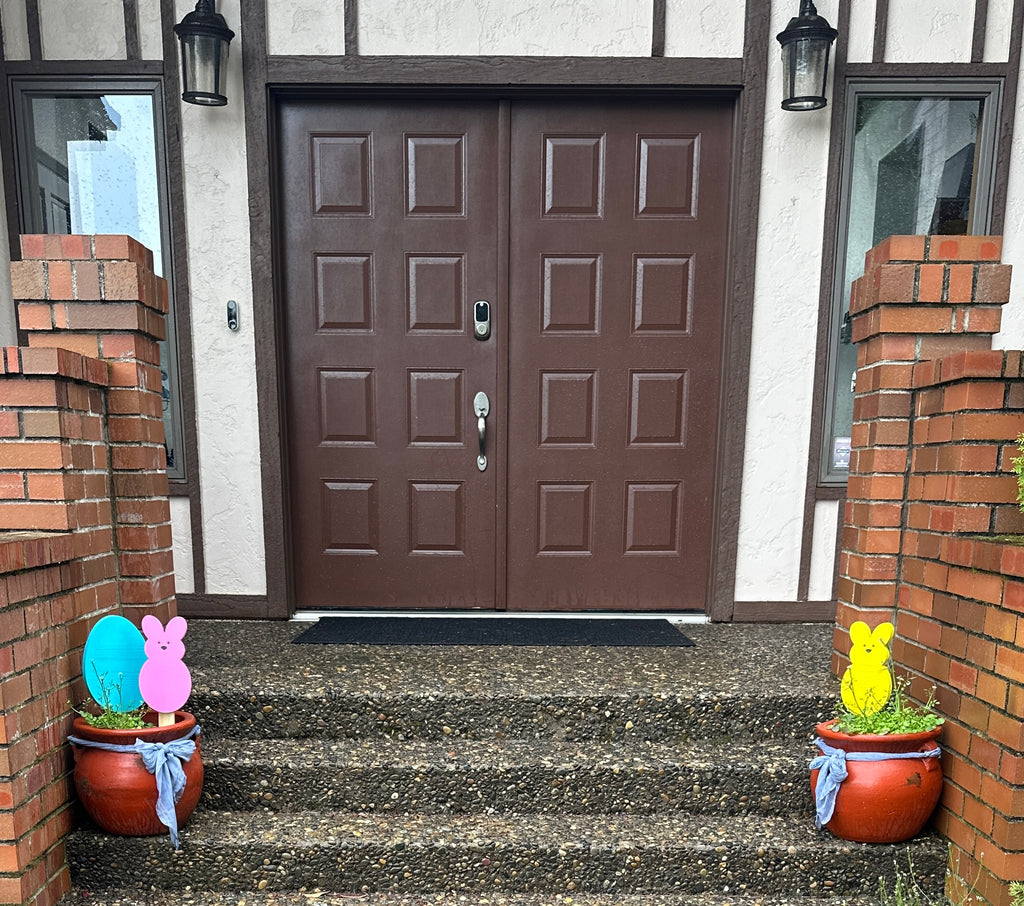 Brown front door porch with Blue Egg & Yellow peeps bunny & Pink Peeps Bunny 18 inch yard stakes in potted plants
