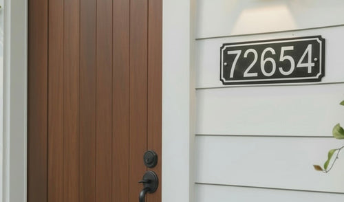 Brown door with black handle and house number sign on a white wall