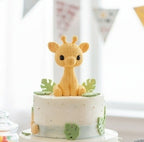 Small cake with a 3d printed "knitted" style giraffe on top in a indoor party setting