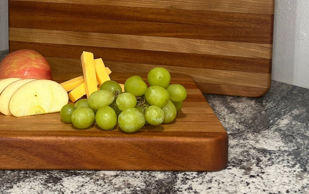 Zoomed in of Mahogany block cutting board with cherry stripe displaying grapes, cheese and apple slices to show wood grain