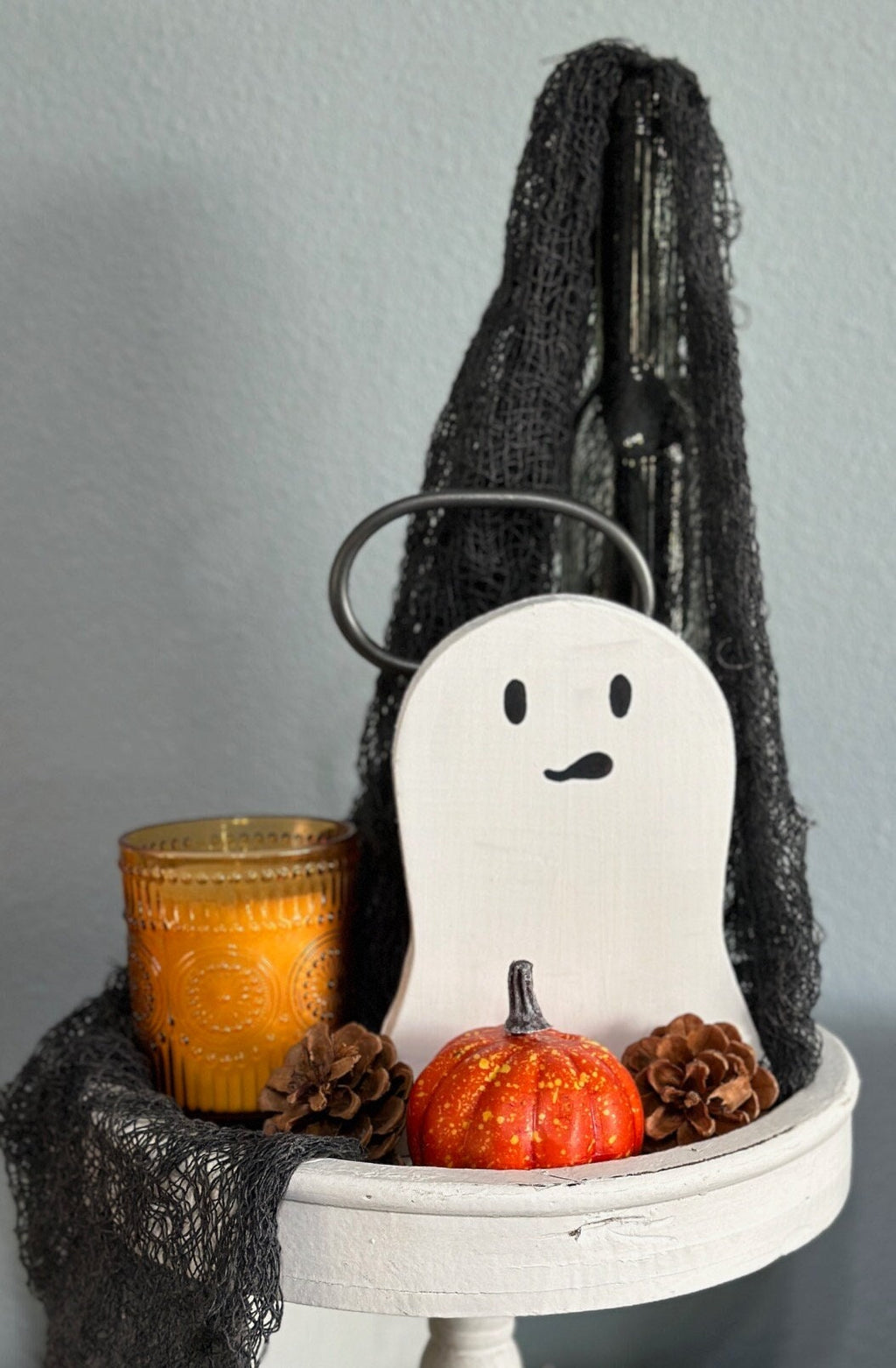wood painted ghosts in halloween tiered tray display with black netting, candle, pumpkin and pine cone