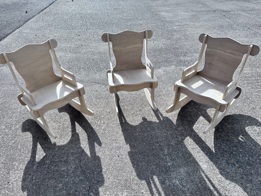 3 unfinished toddler rocking chairs outside with the sun casting shadows on the ground of each chair.