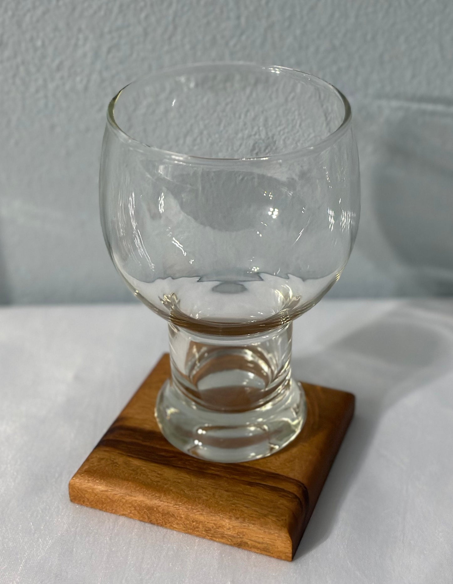 Close up of a drink glass sitting on a Brazil wood coaster.