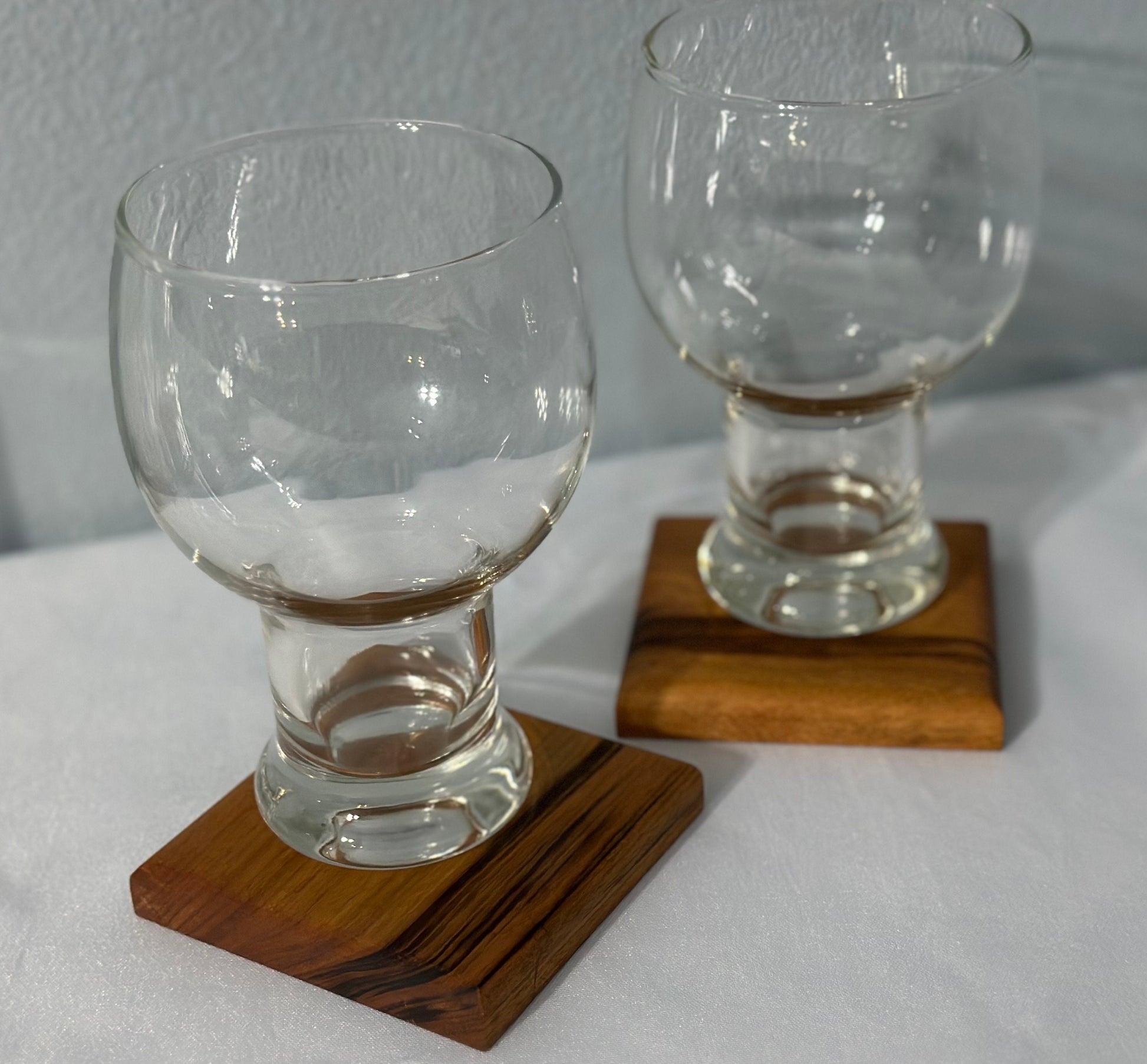 Two glasses displayed on two Brazil wood coasters.