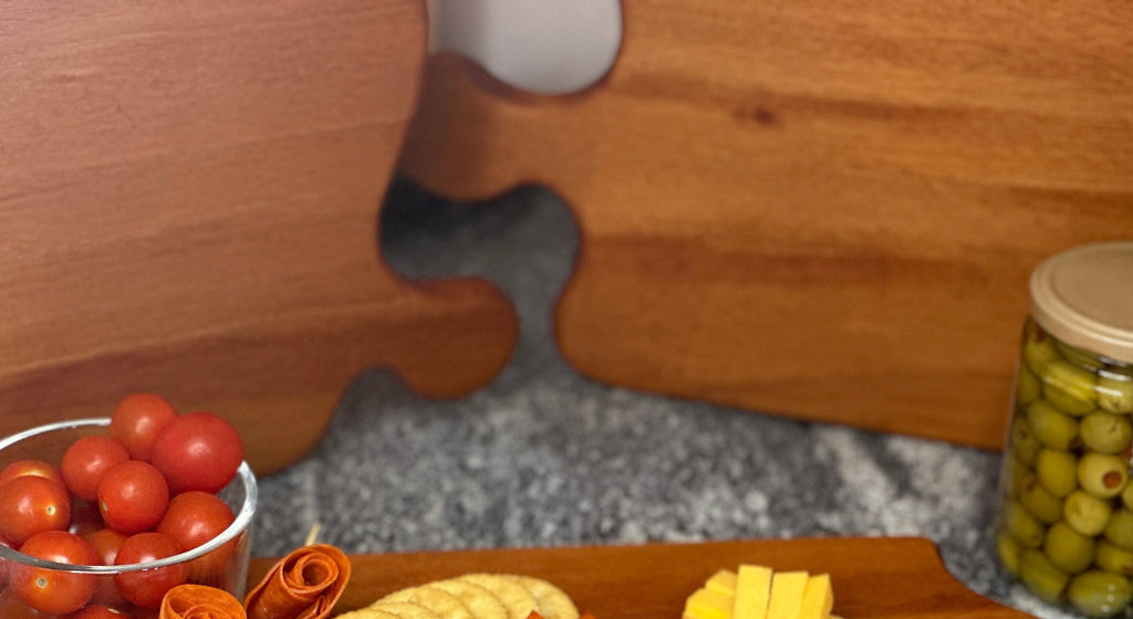 Zoomed in display of 3 Mahogany red hardwood paddle shaped charcuterie boards with cherry tomato, cheese, meat, olives and crackers