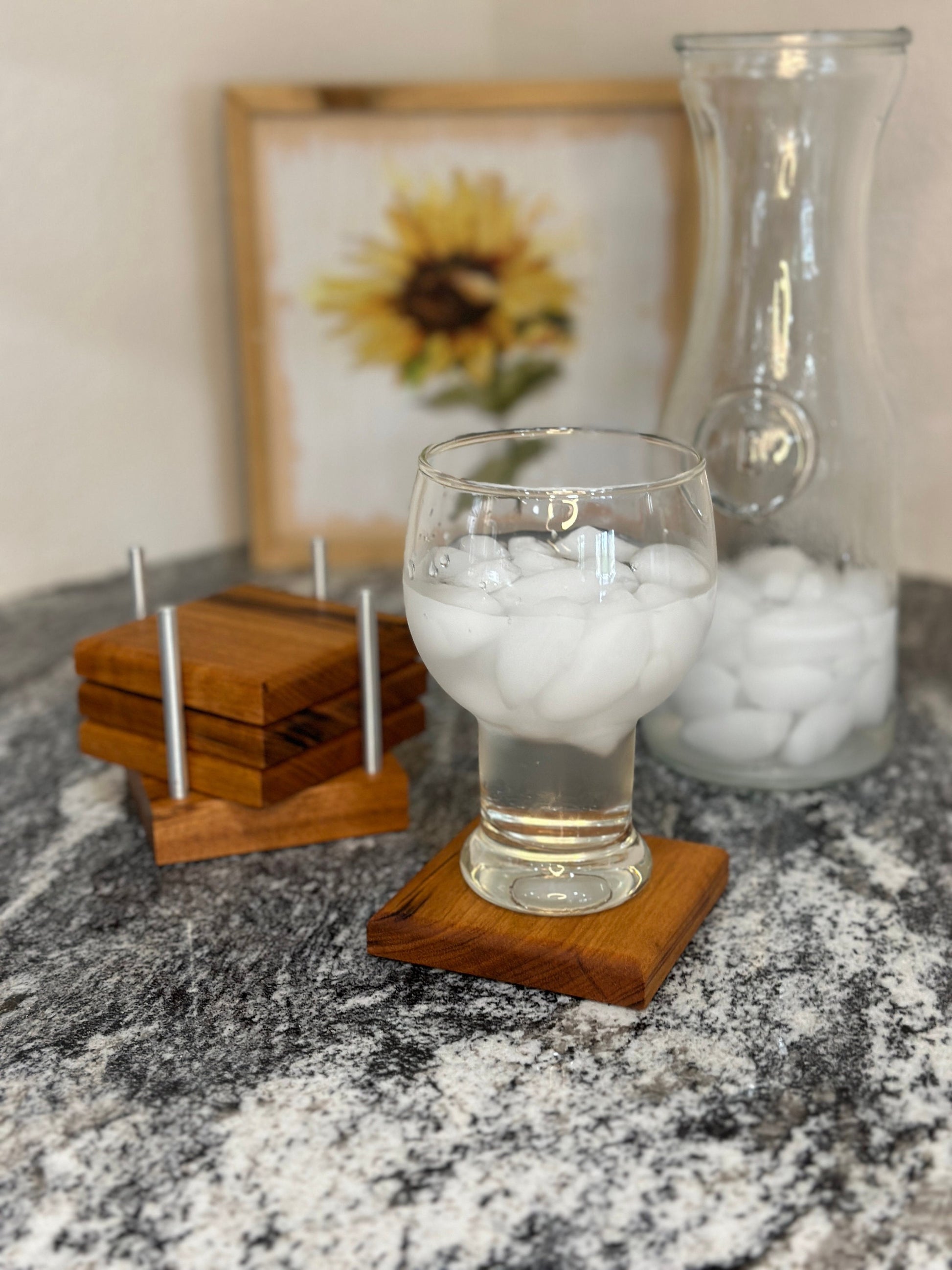 Glass of ice water sitting on a coaster, next to a vase and coaster holder.