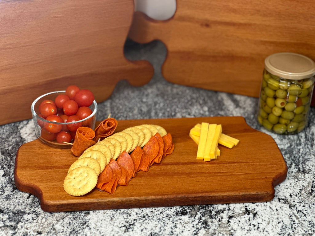 Mahogany red hardwood tray style charcuterie boards with cherry tomato, meat, olive jar, cheese and crackers