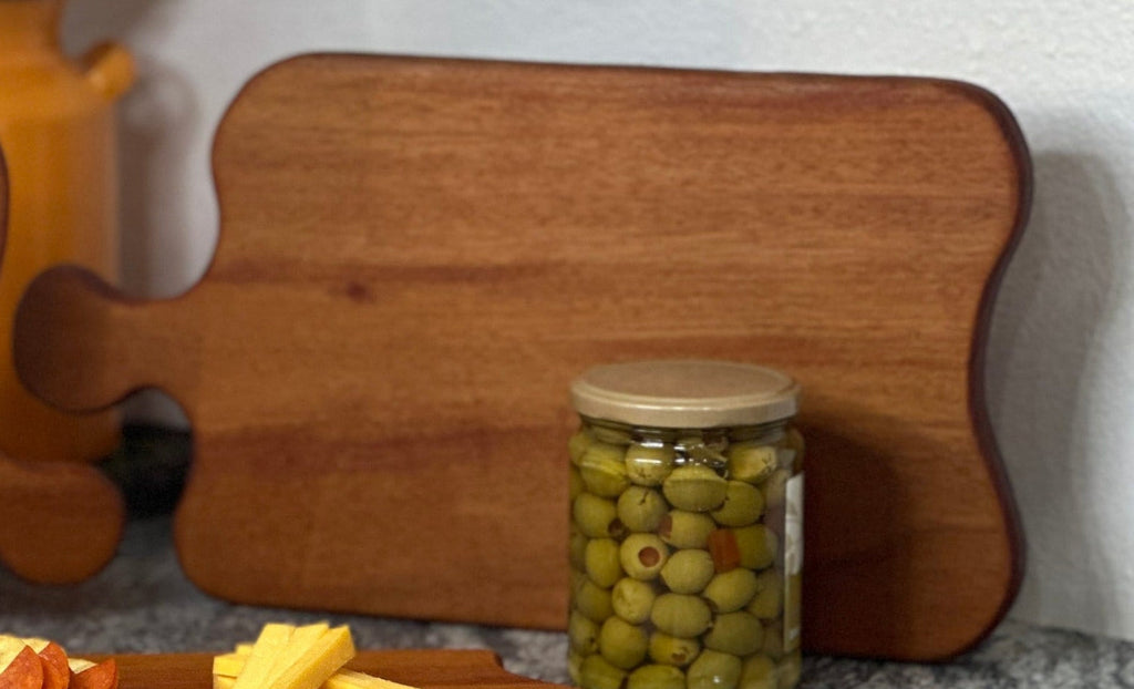 Mahogany red hardwood paddle shaped charcuterie board with olives and cheese