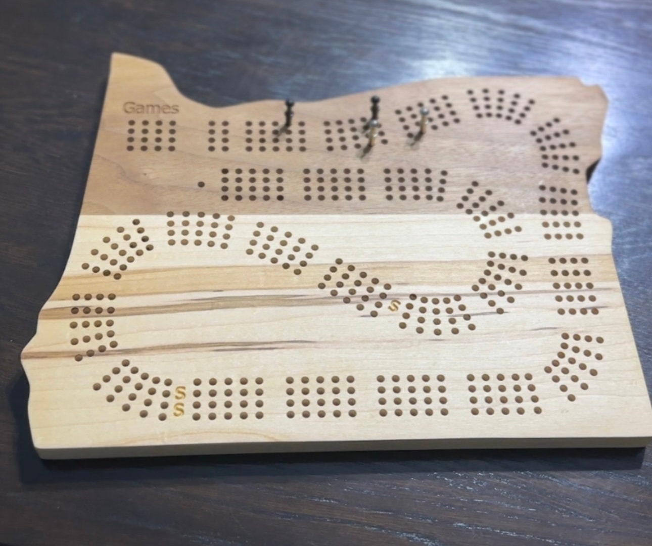 A 4player Oregon shaped cribbage boards made of calico maple and walnut with  metal pins in silver and black