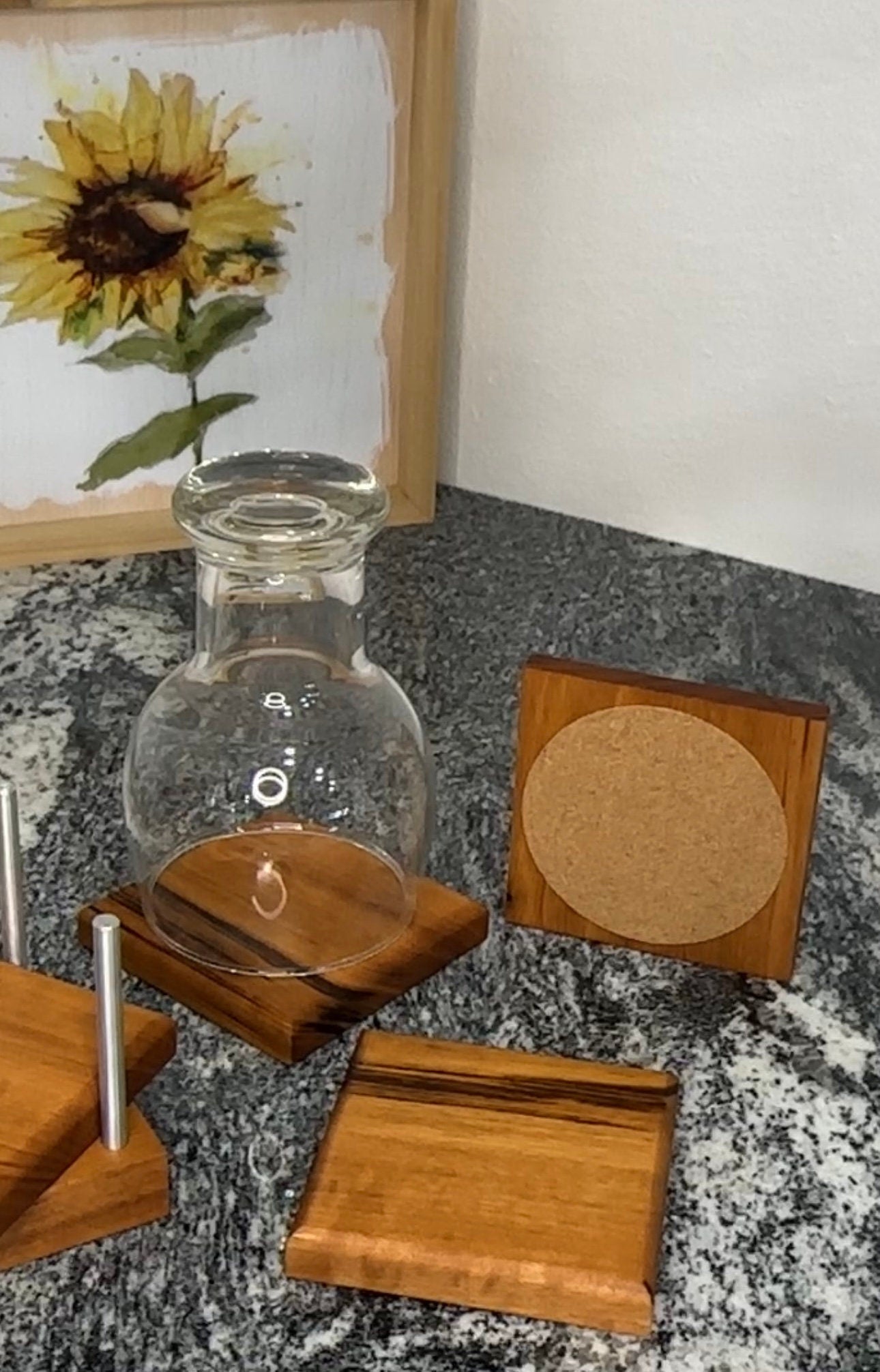 Three coasters displayed on the counter with one water glass sitting on one of them.