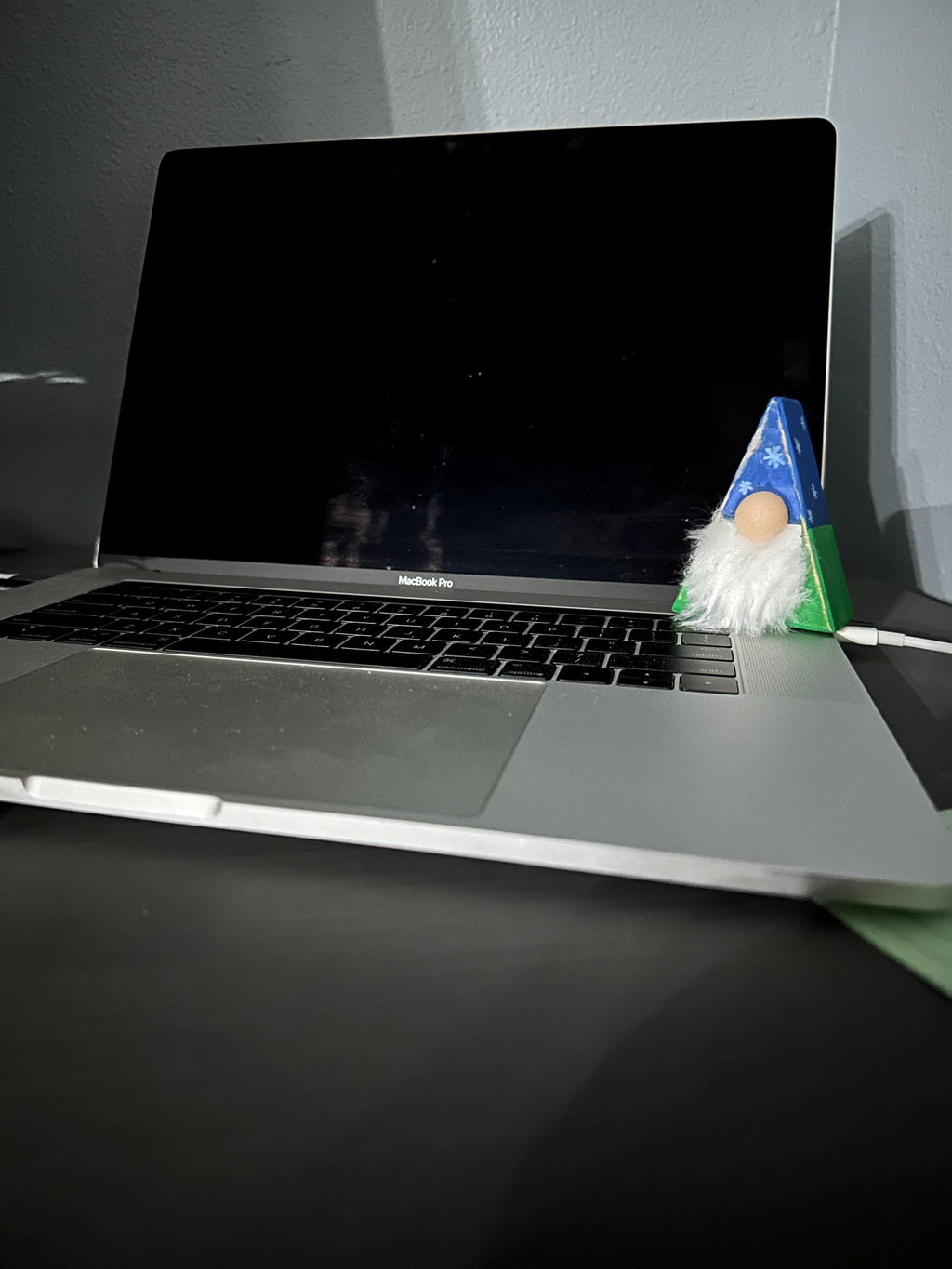triangle gnome with painted antiqued hats sitting a laptop edge