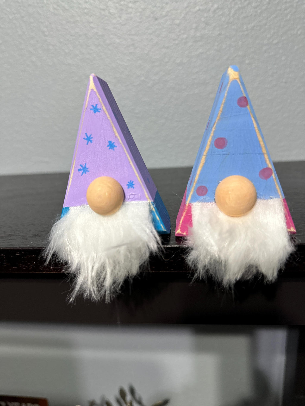 2 triangle gnomes with painted antiqued hats sitting on a shelf