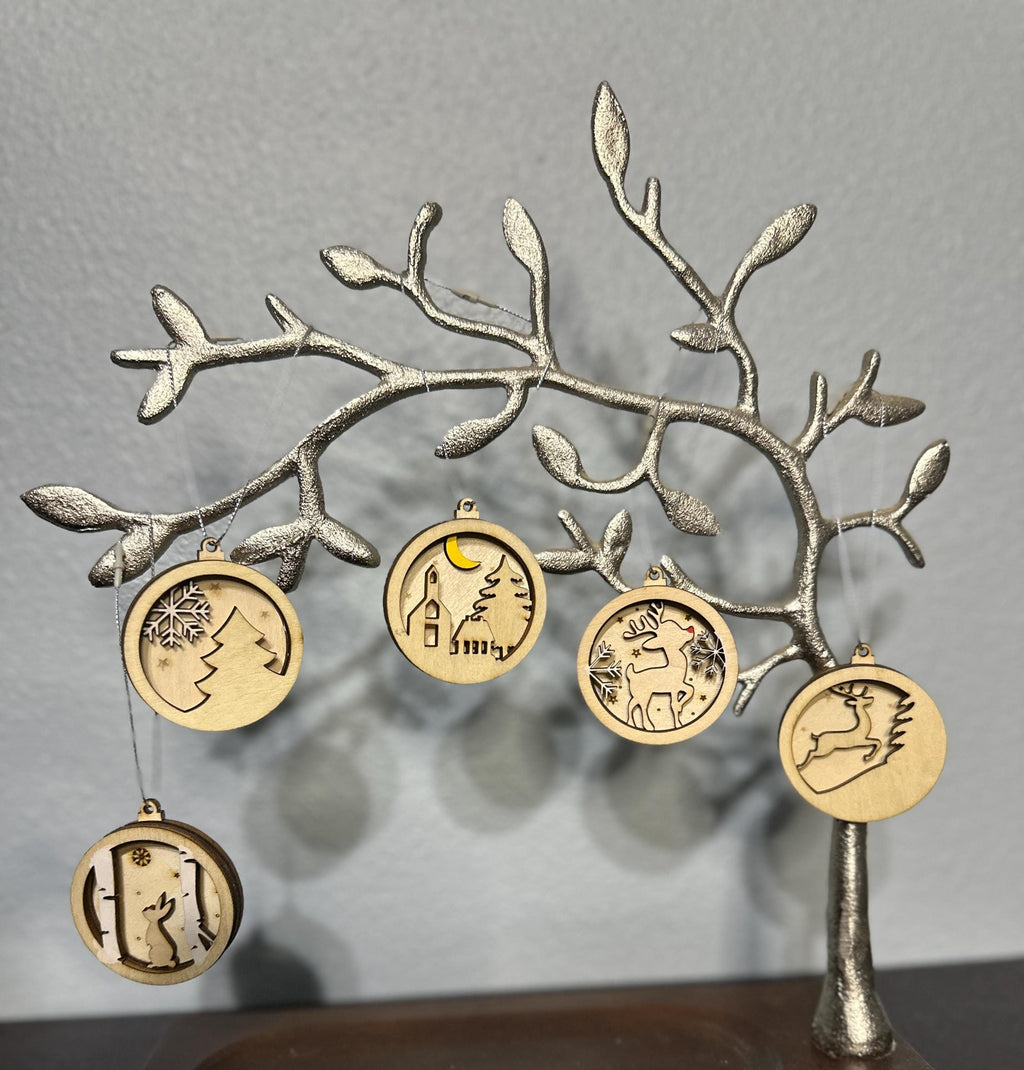 Silver tree displaying a set of wooden layered Christmas ornaments.