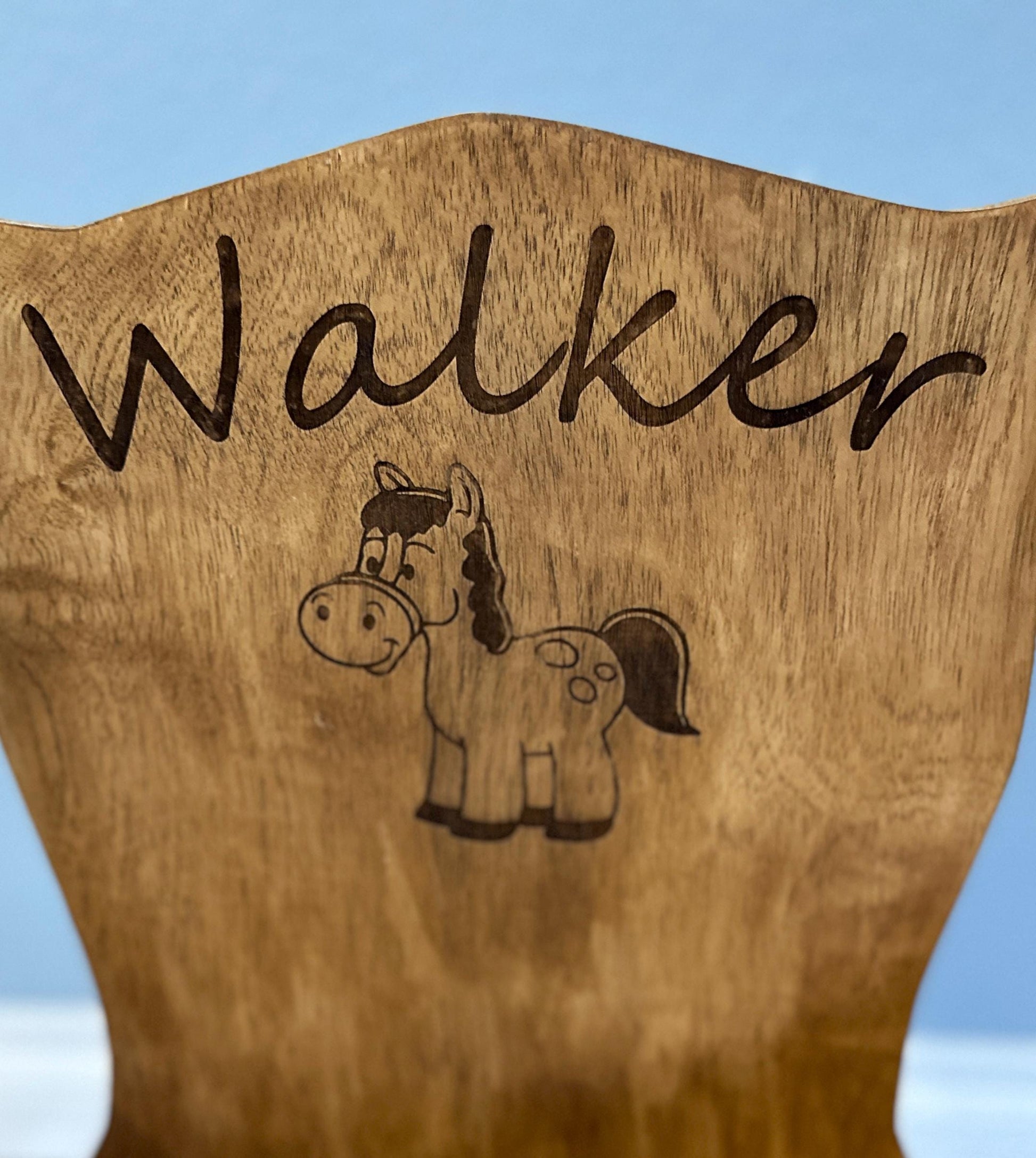 Close up of the rocking chair back showing the laser engraving of "Walker" and the cartoon horse.