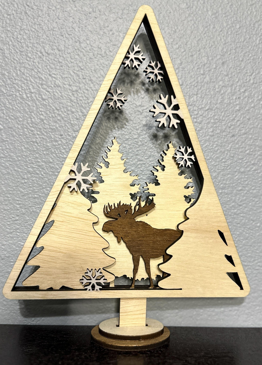 Wood layered triangle decor with stained dark moose with tree and white painted snowflake accents